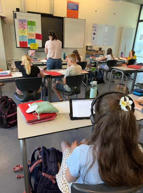 Schülerin im Klassenraum mit iPad und Kopfhörern — Silytics liest ihr den Text vor, während die Klasse weiterarbeitet